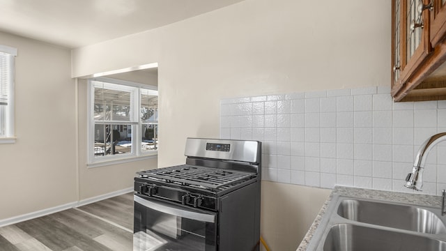 kitchen featuring wood finished floors, a sink, baseboards, light countertops, and gas range