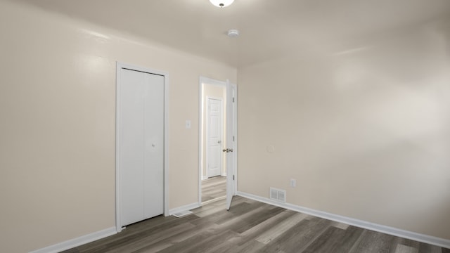 unfurnished bedroom with baseboards, a closet, visible vents, and wood finished floors