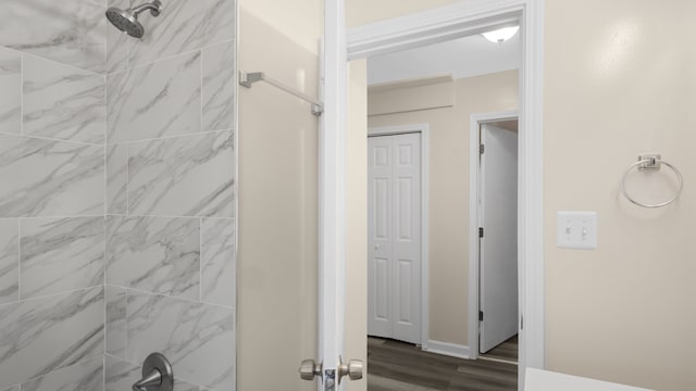 full bathroom with a tile shower and wood finished floors