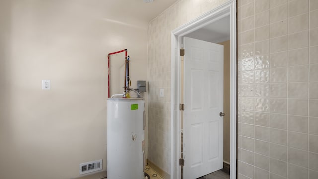 utility room featuring water heater and visible vents