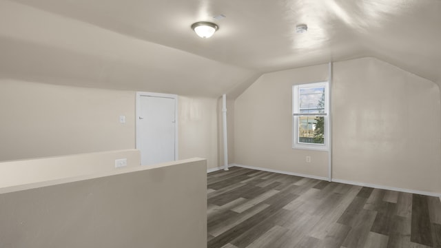 bonus room with baseboards, vaulted ceiling, and dark wood-type flooring