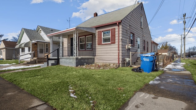 bungalow-style home with covered porch, a chimney, and a front lawn