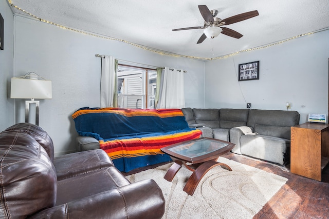 living room with ceiling fan, a textured ceiling, and wood finished floors