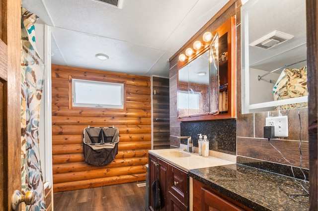 bathroom with wood finished floors, vanity, visible vents, log walls, and decorative backsplash