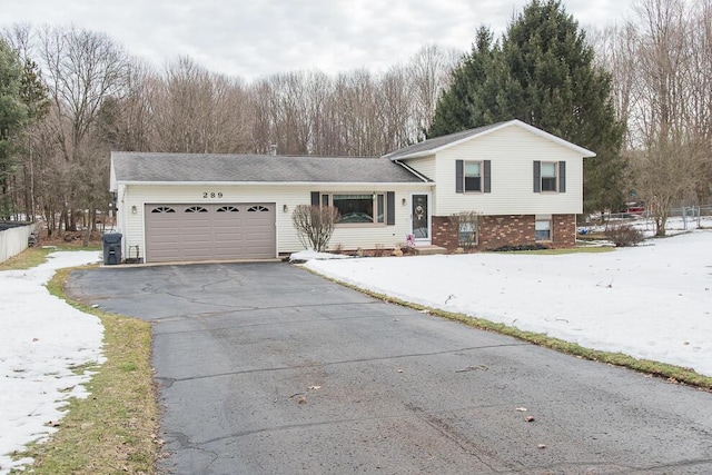 tri-level home with a garage, aphalt driveway, and brick siding