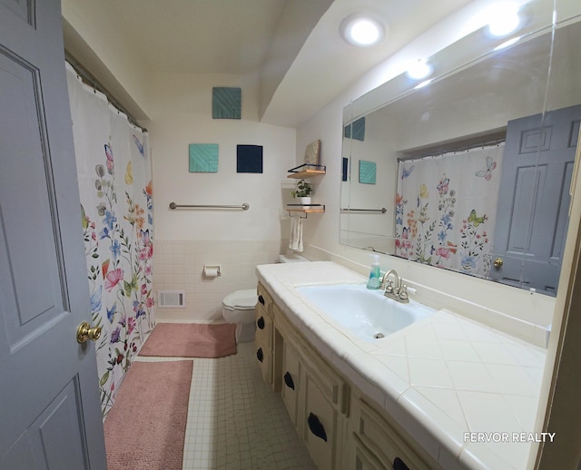 bathroom featuring tile walls, visible vents, toilet, wainscoting, and vanity