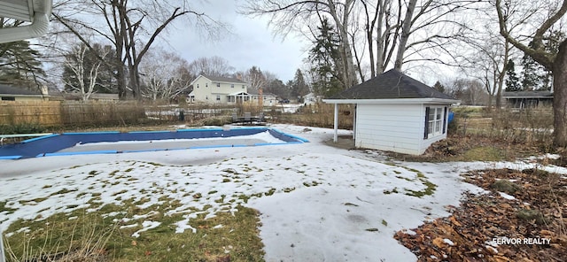 yard layered in snow with a fenced in pool, an outbuilding, and a fenced backyard