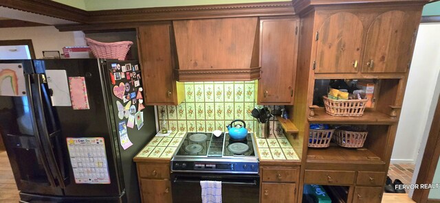 kitchen with brown cabinetry, tile countertops, custom range hood, black appliances, and backsplash