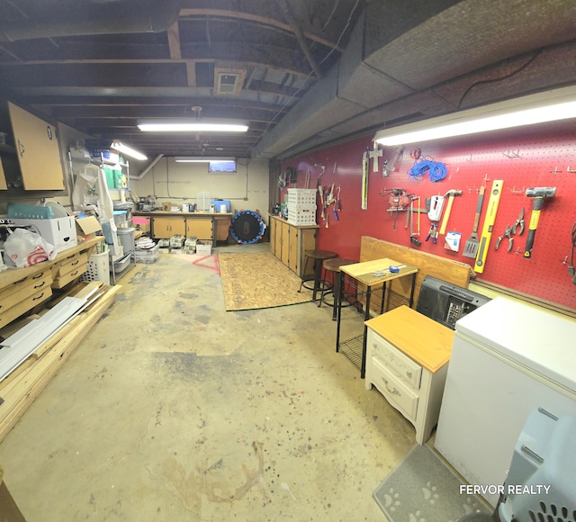 below grade area with a workshop area and white refrigerator