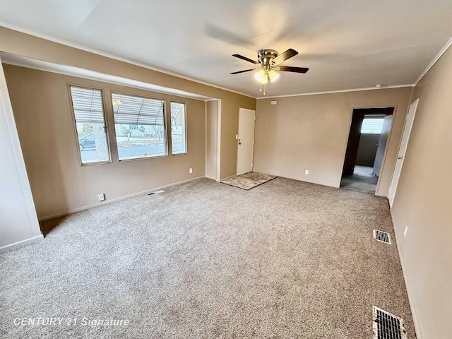 carpeted spare room featuring ceiling fan, visible vents, and ornamental molding