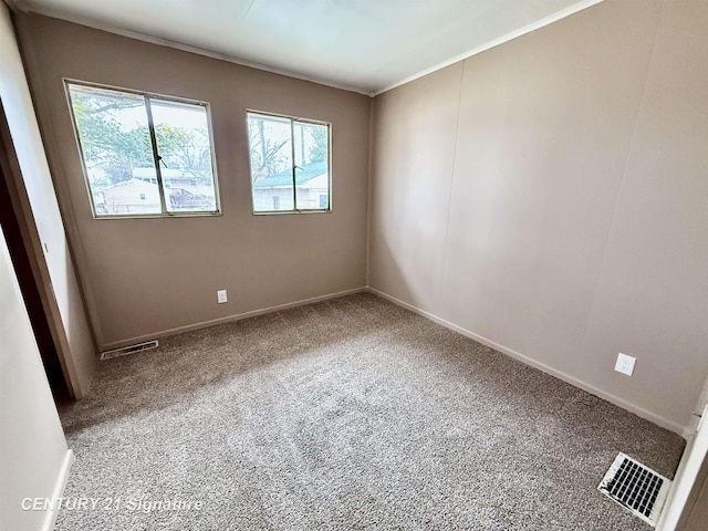 carpeted spare room with visible vents, crown molding, and baseboards