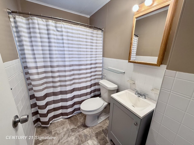 bathroom with crown molding, tile walls, toilet, wainscoting, and vanity