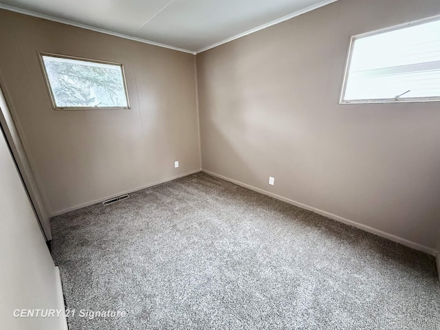 spare room with carpet floors, ornamental molding, visible vents, and baseboards