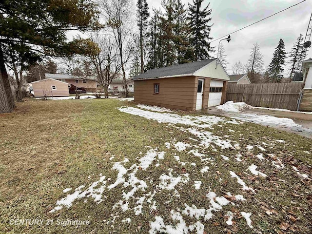 snowy yard with a garage, fence, and an outdoor structure