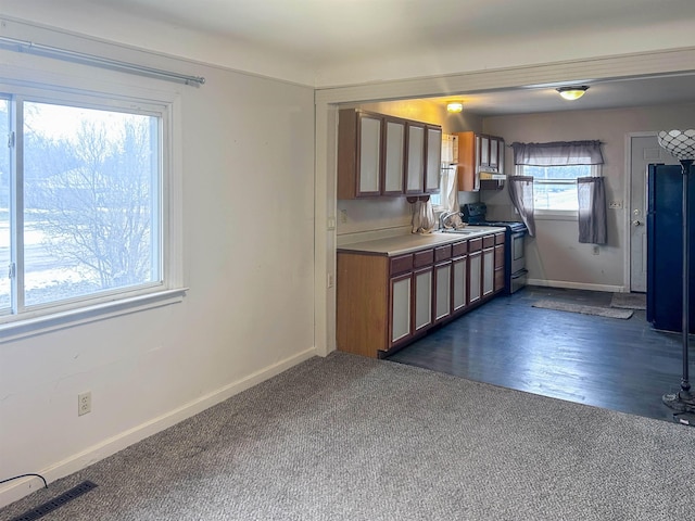 kitchen with a sink, baseboards, brown cabinets, and electric stove