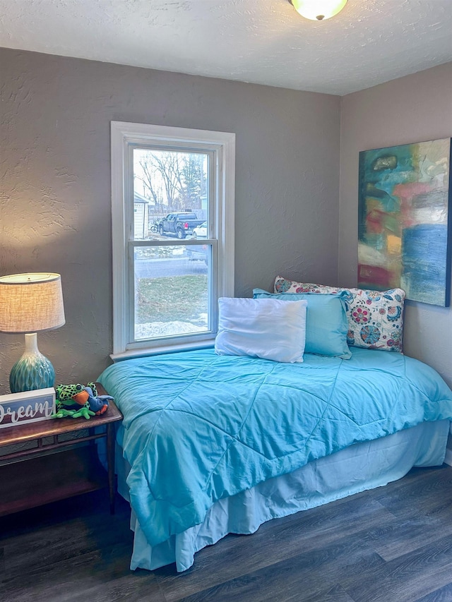 bedroom featuring a textured ceiling, a textured wall, and wood finished floors