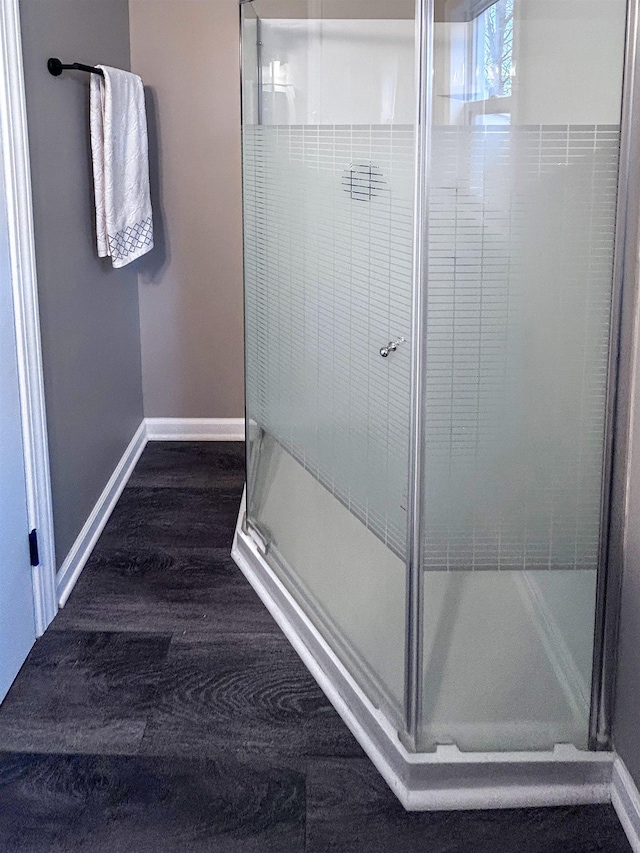 bathroom featuring a shower stall, baseboards, and wood finished floors