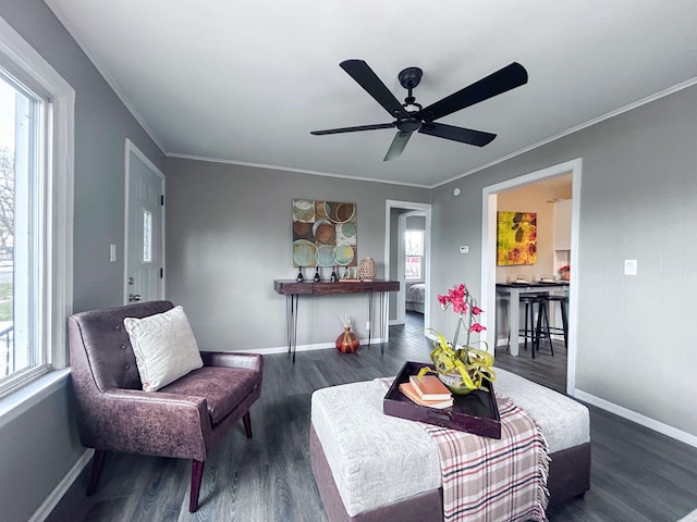 sitting room featuring dark wood-style floors, crown molding, a ceiling fan, and baseboards