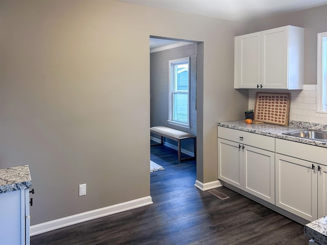 kitchen featuring a sink, white cabinets, baseboards, backsplash, and dark wood-style floors