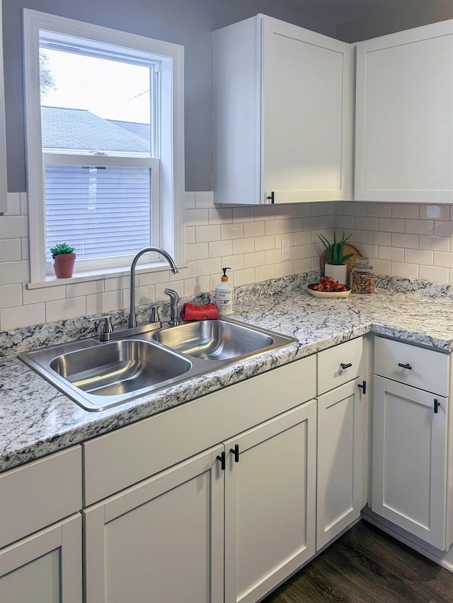 kitchen with tasteful backsplash, light countertops, dark wood-type flooring, white cabinets, and a sink