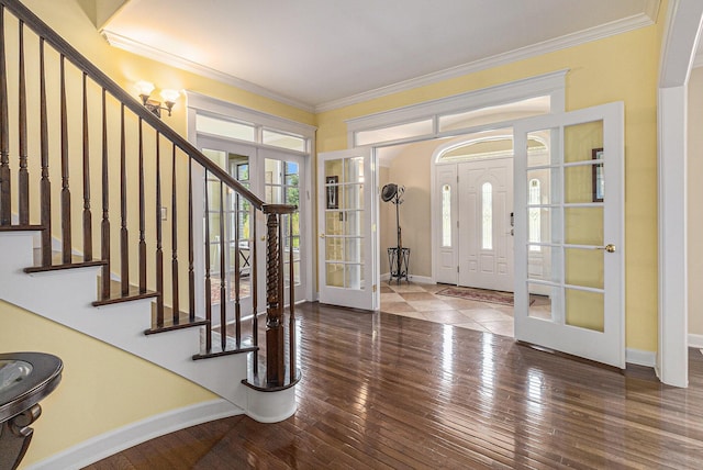 foyer entrance featuring wood-type flooring, baseboards, crown molding, and french doors