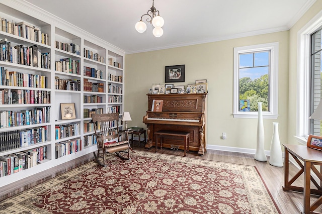 sitting room with crown molding, an inviting chandelier, wall of books, wood finished floors, and baseboards