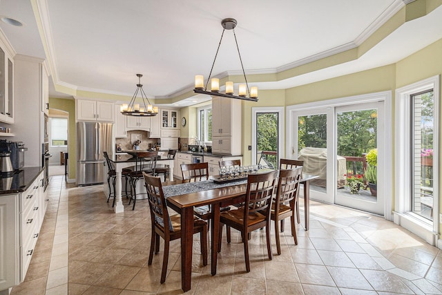 dining room with light tile patterned floors, crown molding, a tray ceiling, and a notable chandelier