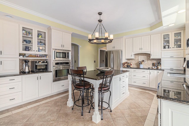 kitchen featuring ornamental molding, stainless steel appliances, backsplash, and a kitchen breakfast bar