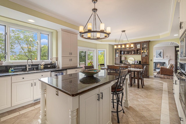 kitchen with a tray ceiling, a breakfast bar, a sink, and a glass covered fireplace