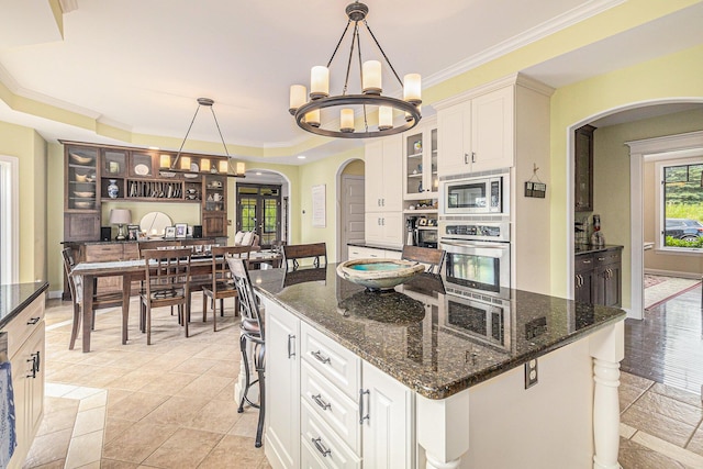 kitchen with ornamental molding, appliances with stainless steel finishes, glass insert cabinets, and white cabinetry