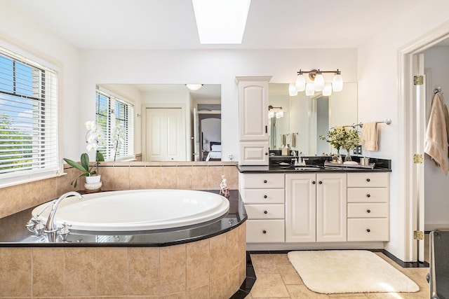 full bath with a skylight, tile patterned flooring, vanity, and a bath