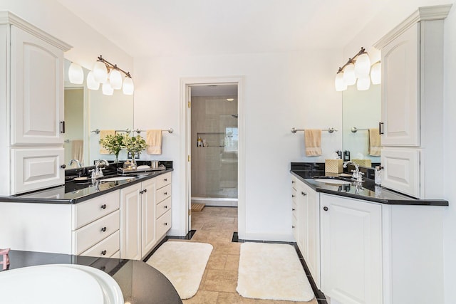 bathroom featuring baseboards, two vanities, a sink, and a shower stall