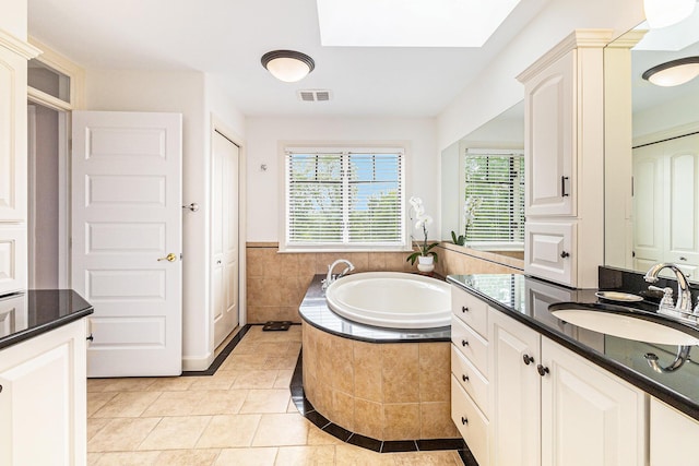 full bathroom featuring a skylight, visible vents, a garden tub, tile patterned flooring, and vanity