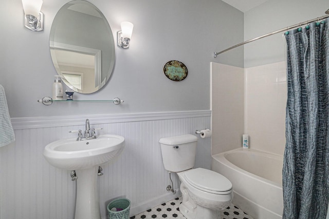 full bath featuring wainscoting, tile patterned floors, toilet, and shower / bathtub combination with curtain