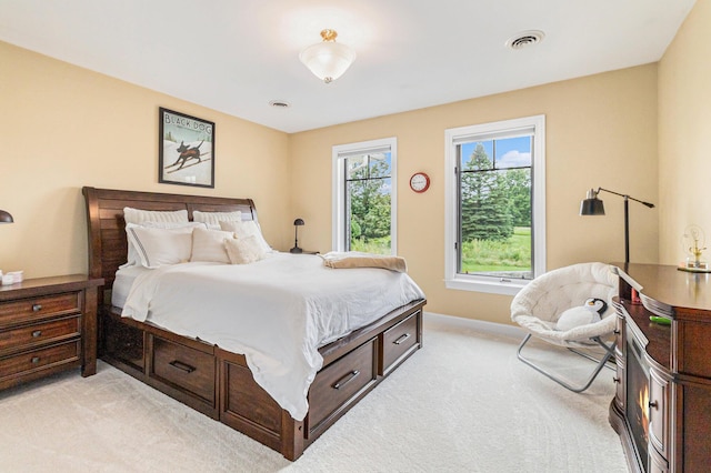 bedroom with baseboards, visible vents, and light colored carpet