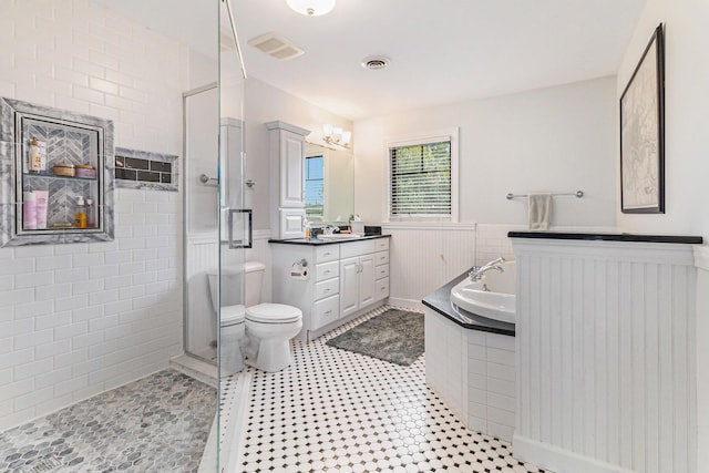 bathroom featuring a garden tub, toilet, vanity, wainscoting, and a shower stall