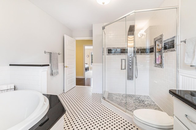 bathroom featuring toilet, a wainscoted wall, vanity, a shower stall, and a bath