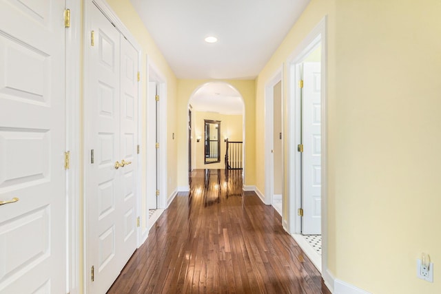 hallway with dark wood-style floors, arched walkways, baseboards, and recessed lighting