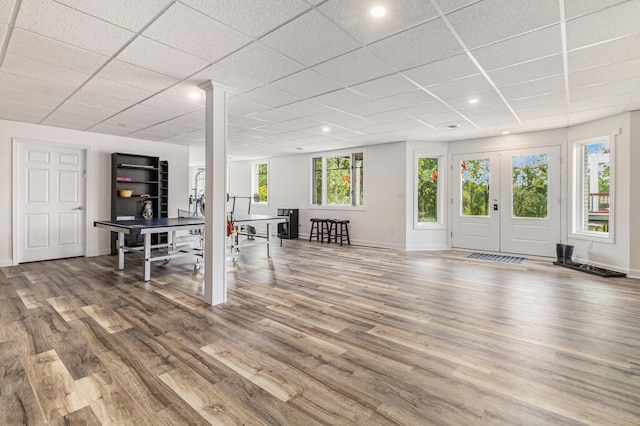 below grade area with baseboards, a drop ceiling, wood finished floors, and french doors