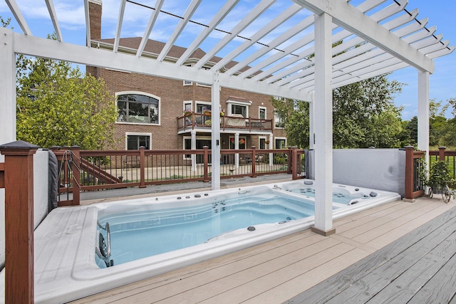 view of swimming pool featuring hot tub deck surround, a pergola, and a wooden deck