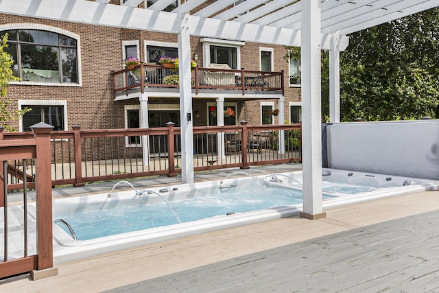 view of pool featuring a pergola, a wooden deck, and hot tub deck surround