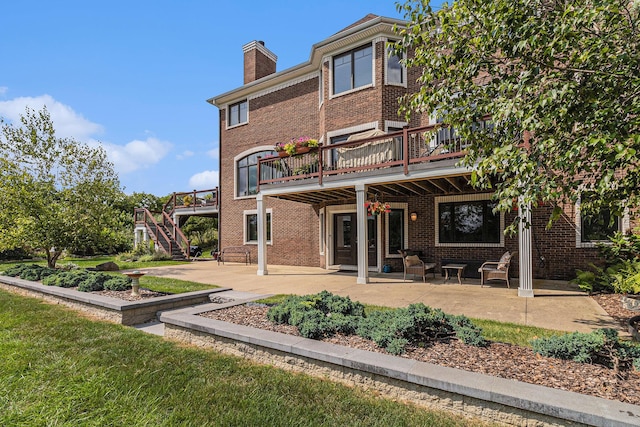 rear view of house featuring a patio area, brick siding, a chimney, and stairs