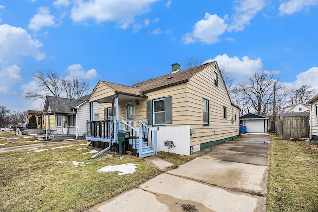 bungalow-style home featuring an outbuilding, a detached garage, a front lawn, and fence