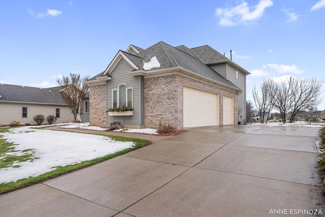 view of side of home with concrete driveway, brick siding, an attached garage, and a shingled roof