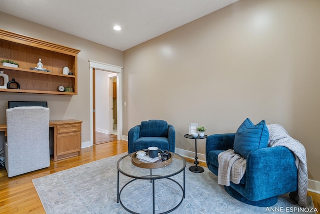 living area with recessed lighting, baseboards, built in desk, and light wood finished floors