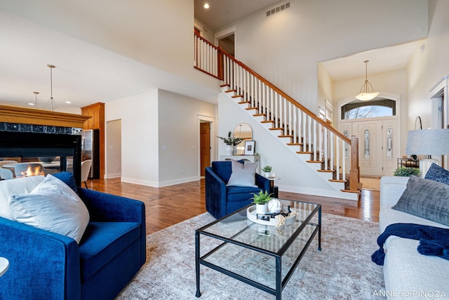 living room with visible vents, stairway, a high ceiling, wood finished floors, and baseboards