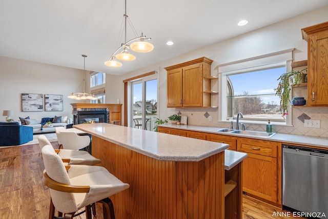 kitchen with a glass covered fireplace, light countertops, stainless steel dishwasher, open shelves, and a sink