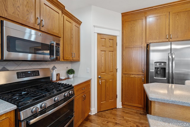 kitchen with tasteful backsplash, appliances with stainless steel finishes, and brown cabinetry