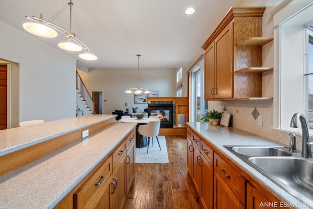 kitchen featuring a sink, brown cabinets, open shelves, dark wood finished floors, and decorative light fixtures