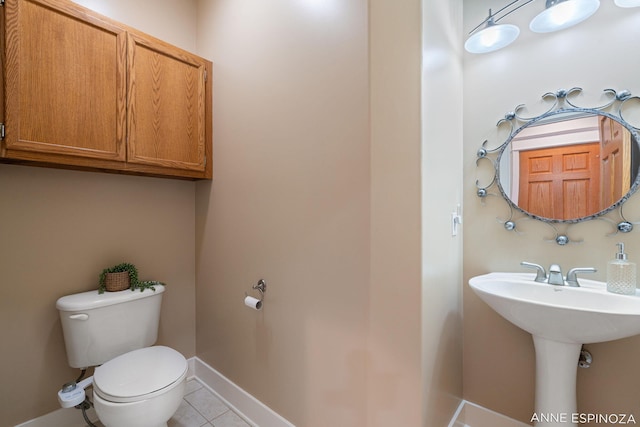 half bathroom with tile patterned flooring, toilet, and baseboards